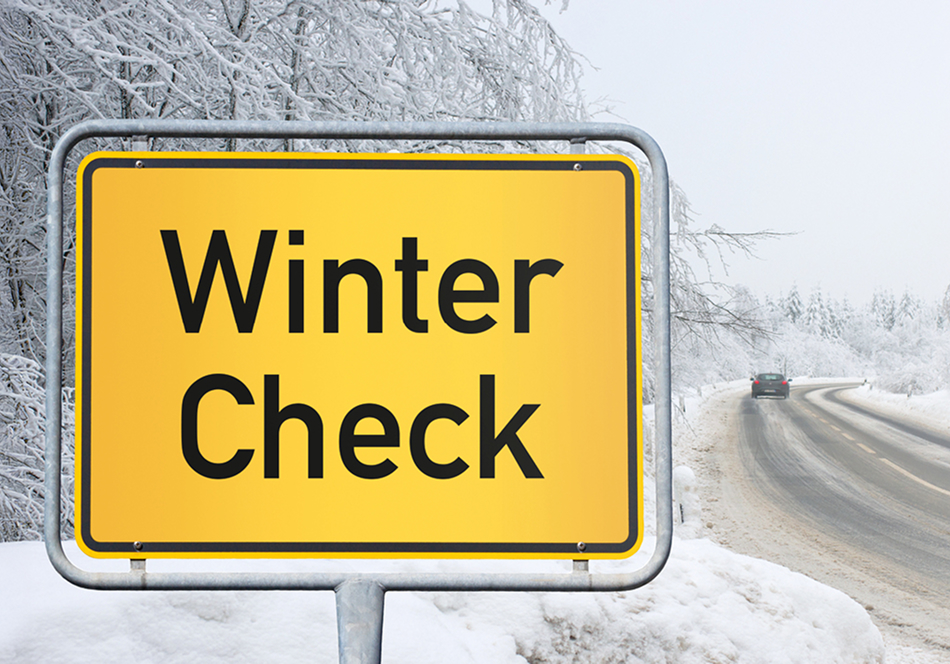 Ein Ortschild mit der Aufschrift Winter-Check in verschneiter Landschaft